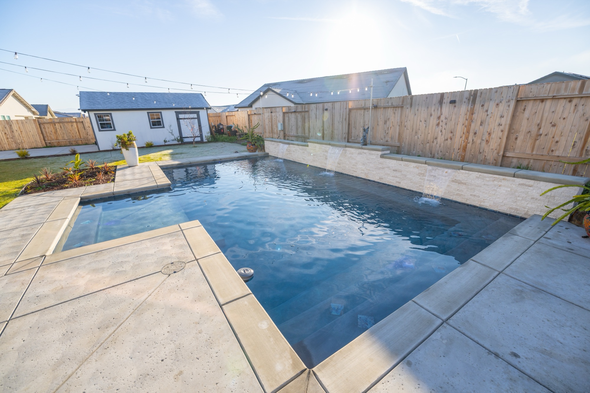 Custom gunite pool with dark plaster and stone wall — Bakersfield, CA