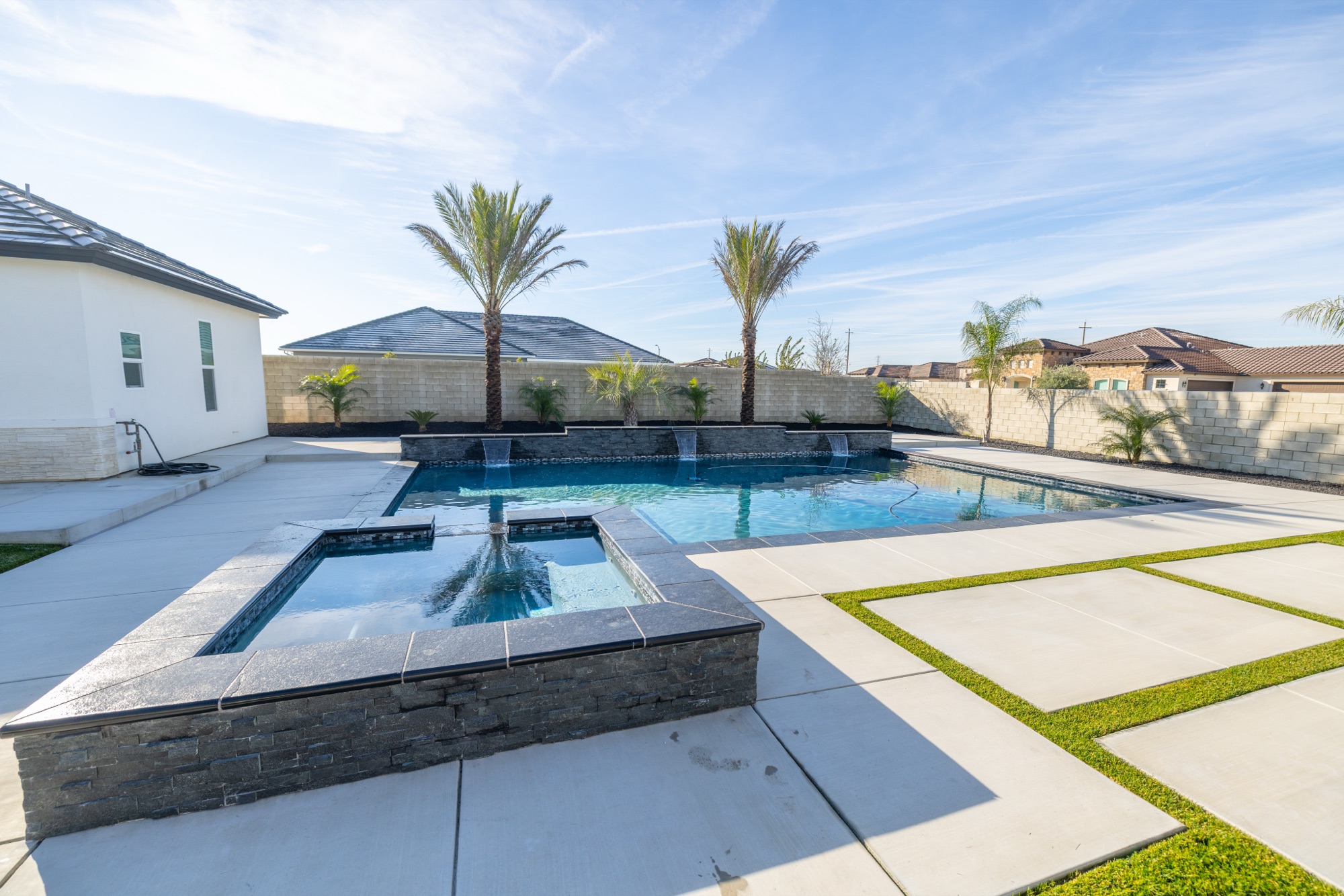 Custom gunite pool with raised stone spa and dual waterfall features — Bakersfield, CA