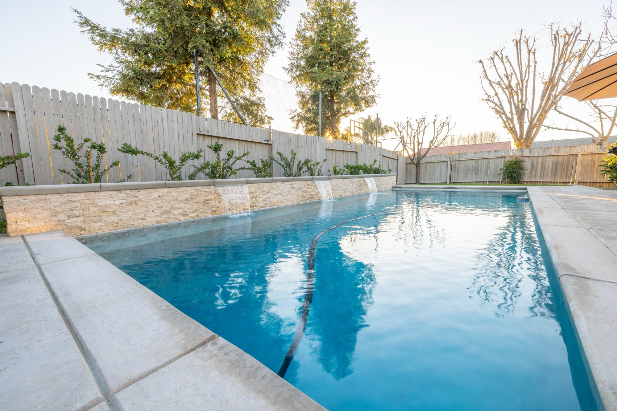 Custom gunite pool with stone wall spillway at dusk — Bakersfield, CA